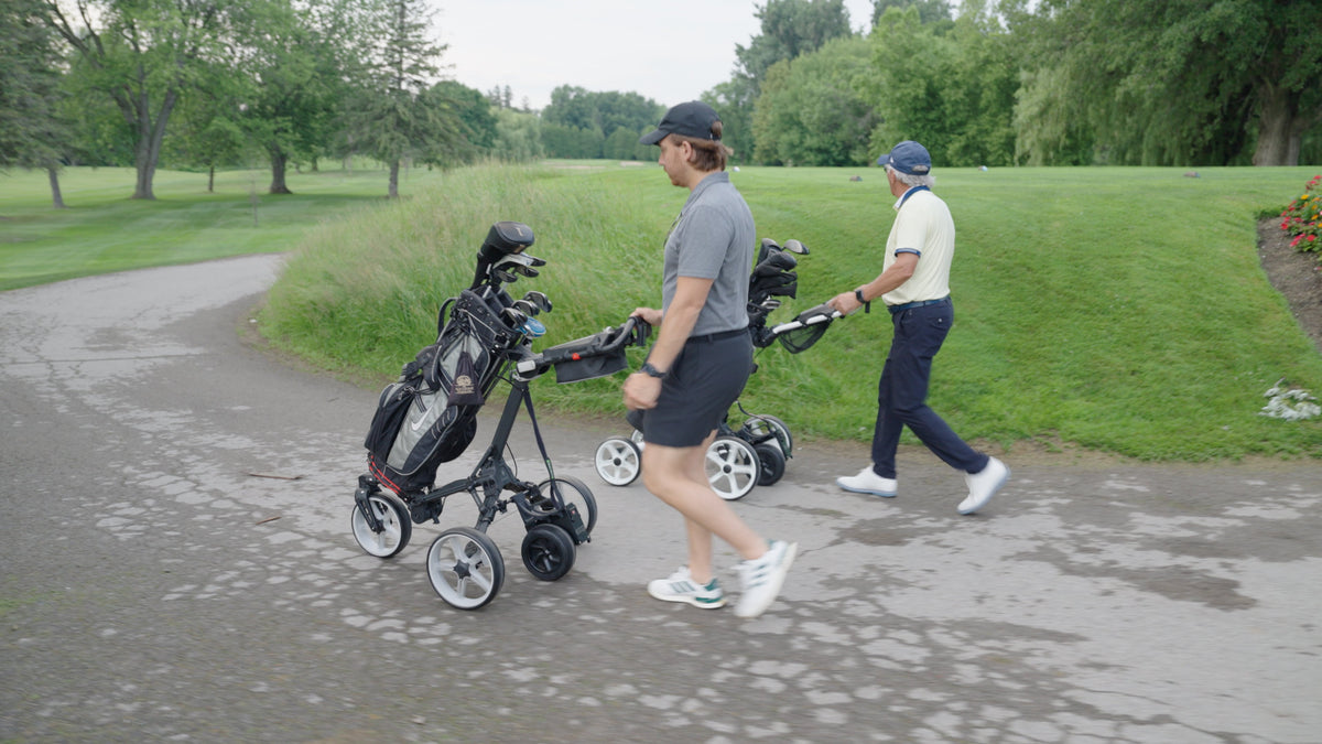 Two golfers walking a cart path with push carts powered by Caddie Wheel electric conversion kits