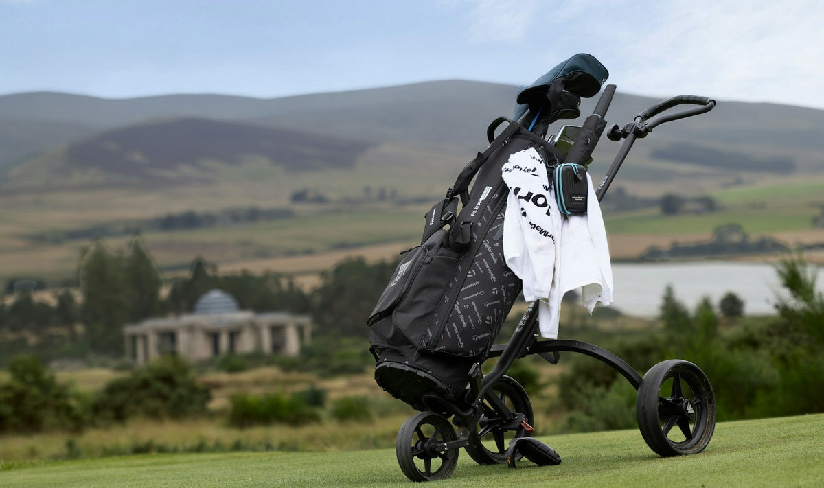 Golf bag on a push cart on a green golf course with rolling hills