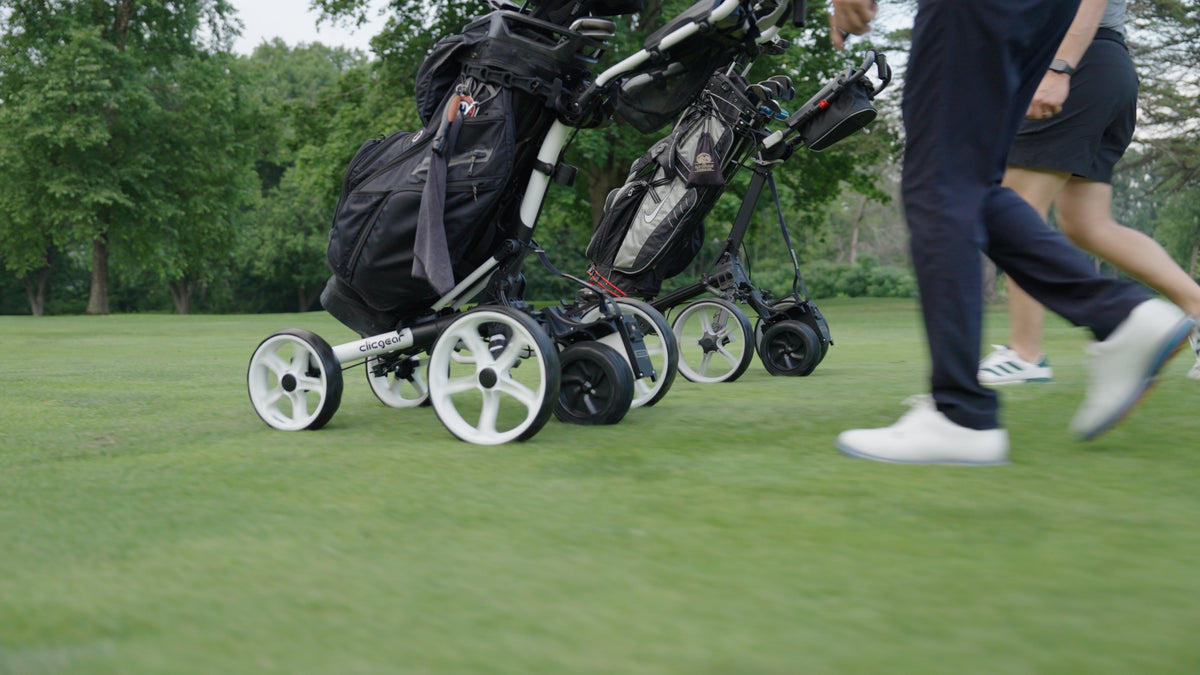 Golfer walking beside a Clicgear push cart powered by a Caddie Wheel on the fairway